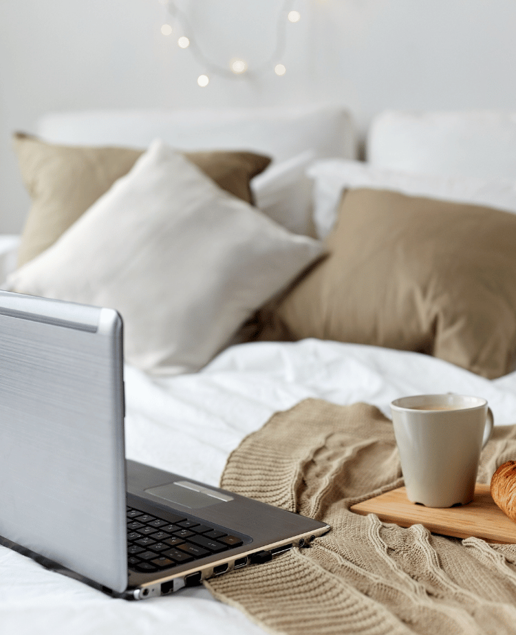 Laptop on bed with coffee