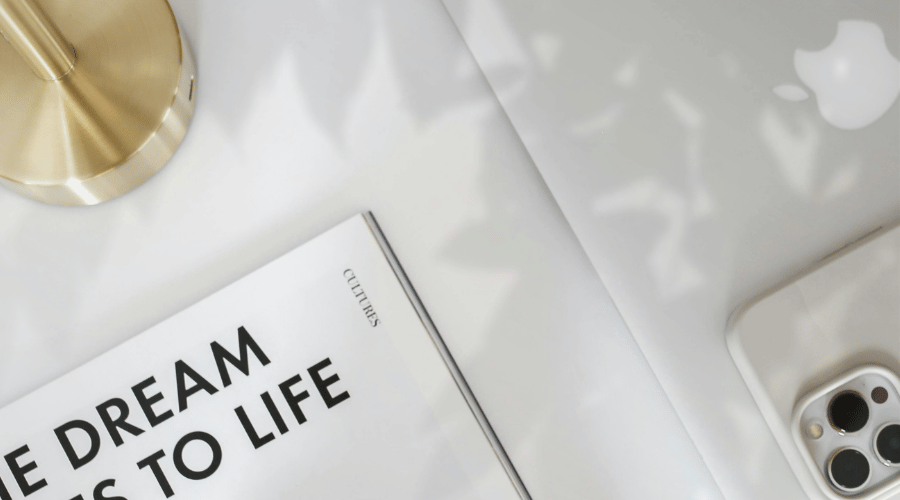 Book on table with gold lamp and iphone with overhead shadow