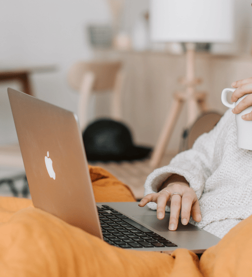 Woman typing on keyboard while drinking coffee